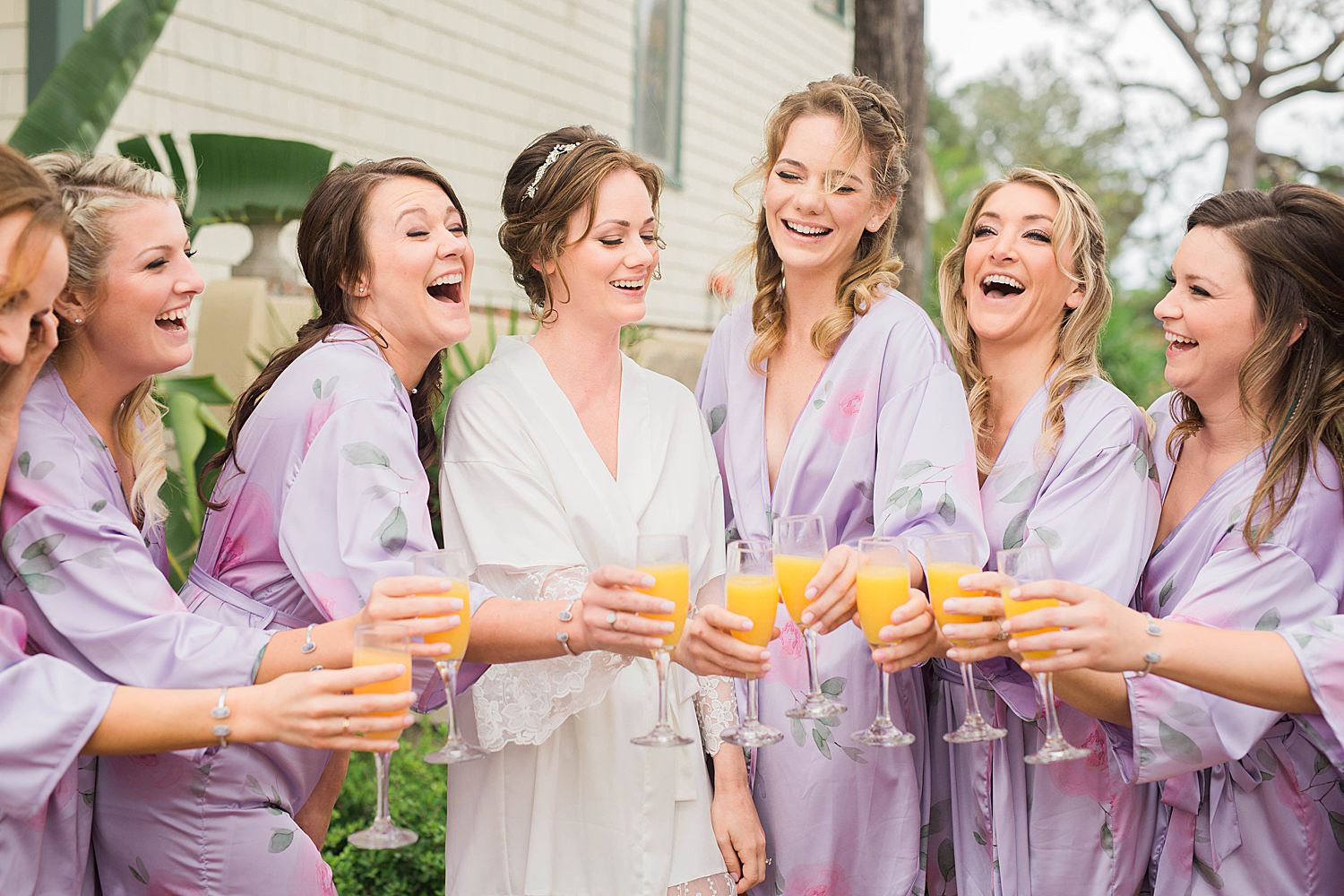 Bride and her bridesmaids share a laugh over a champagne toast