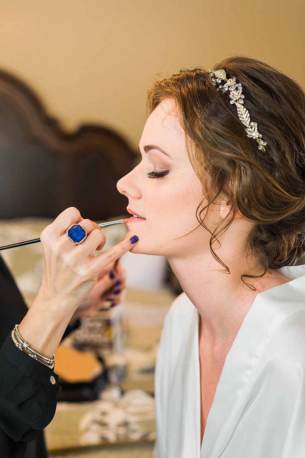 Makeup Artist applies bride's lipstick while getting ready for her wedding