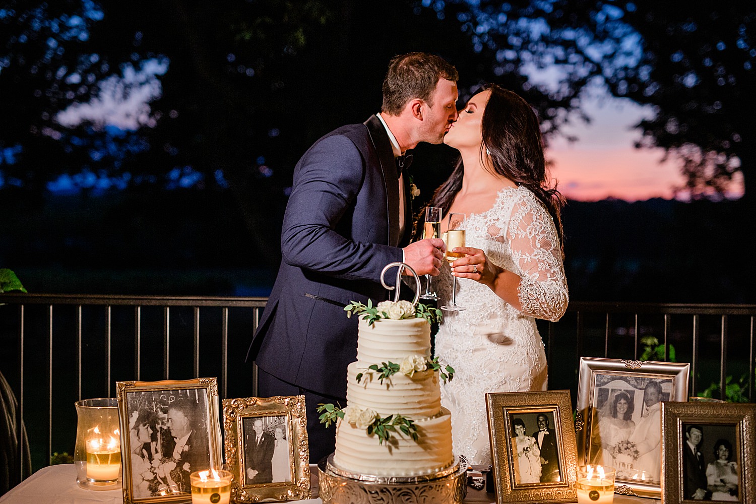 Bride and Groom share a kiss while toasting champagne in front of their wedding cake