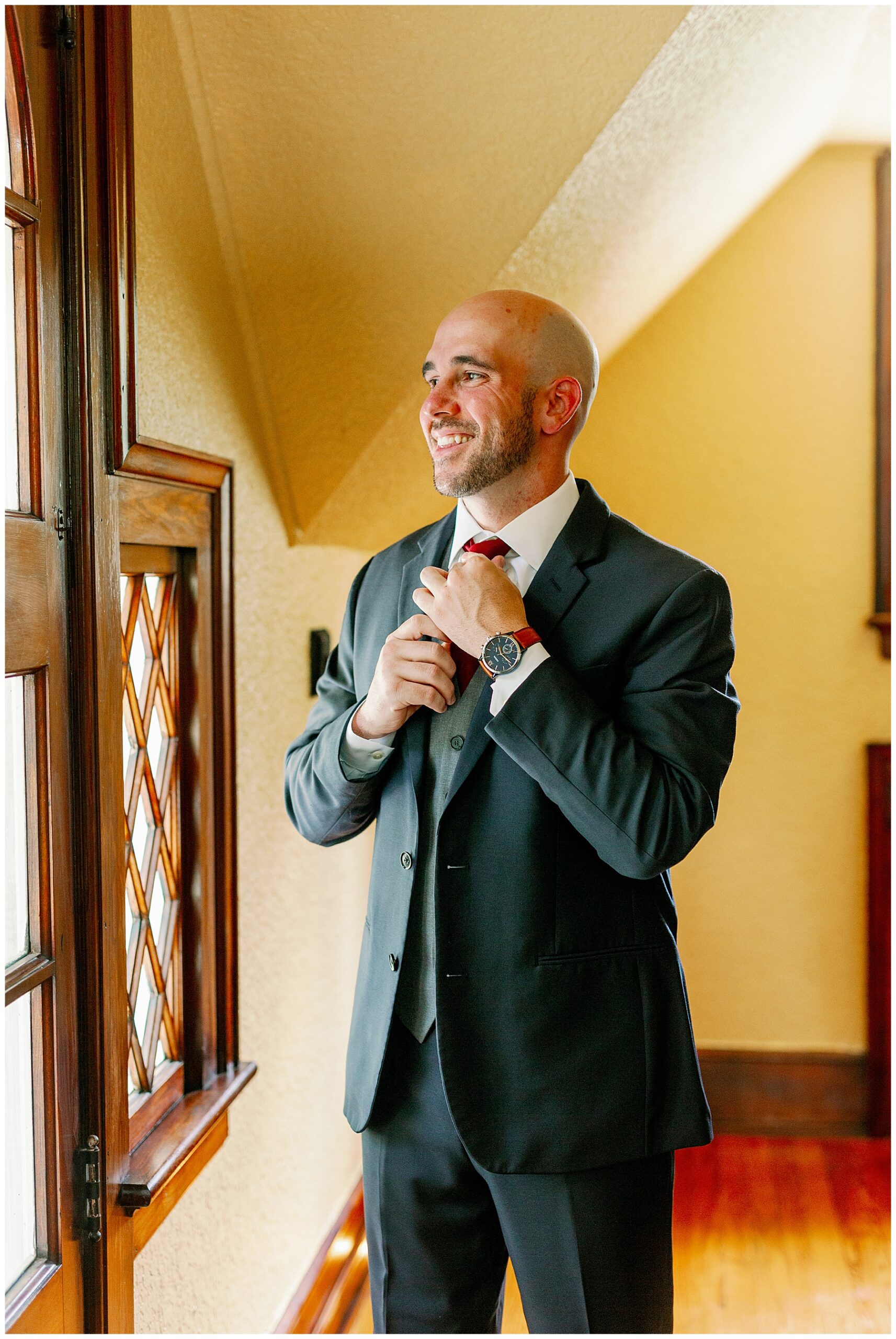 Groom smiles as he puts on the finishing touches for his wedding day suit